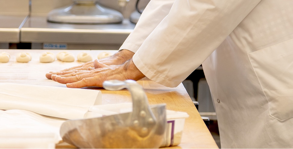 Bäcker bereitet Teig auf einer Arbeitsfläche in der Backstube vor