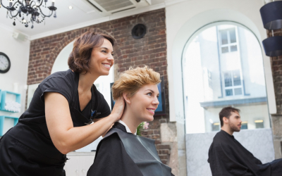 Smiling hairdresser chatting with customer